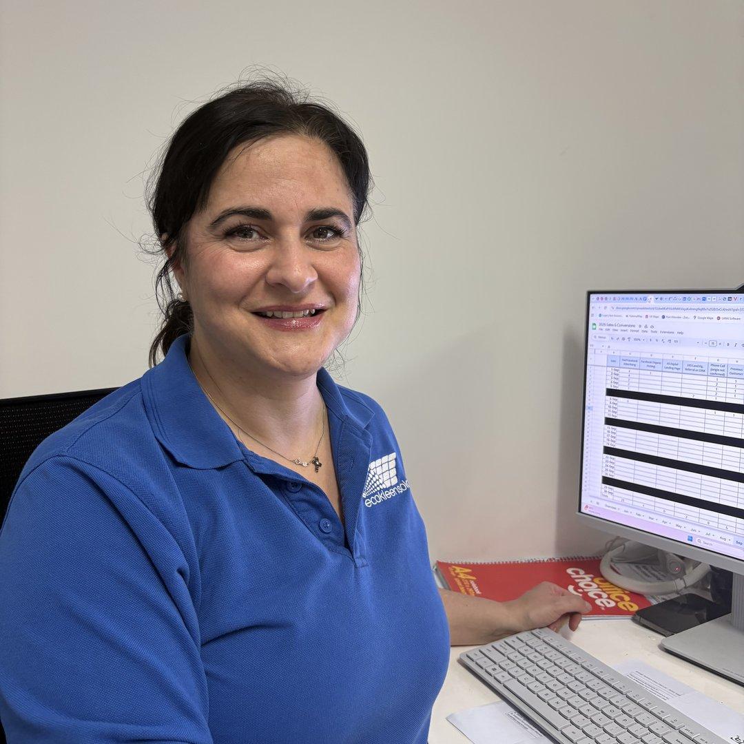 Claudia from EcoKleen Solar seated at her desk working on scheduling spreadsheets at a computer