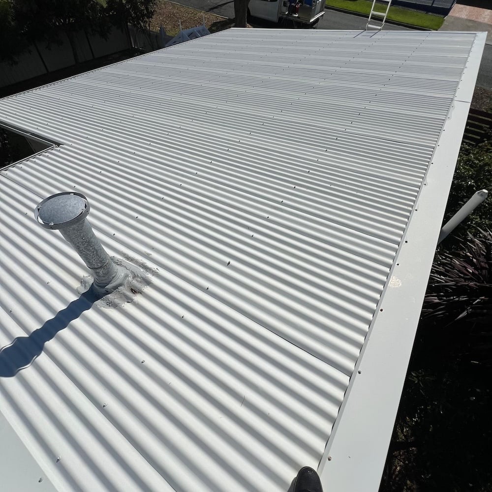 An overhead view of a freshly cleaned, bright white corrugated metal roof, completely free of moss and lichen.